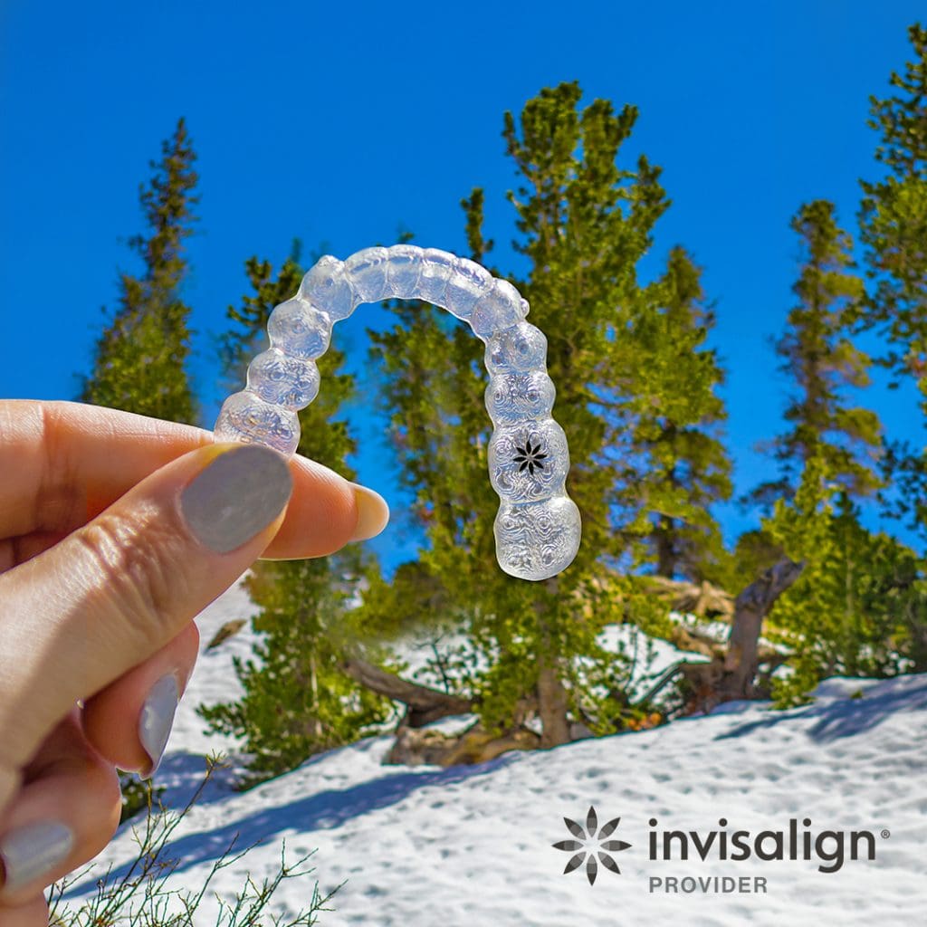 Photo of hand holding invisalign clear aligner.